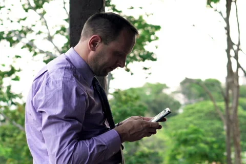 Young businessman using, texting on smartphone  standing on terrace NTSC Stock Footage 51876198