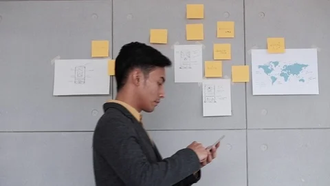 Young Businessman Walking while Using Smartphone in Office. Document Note on Stock Footage 104245494