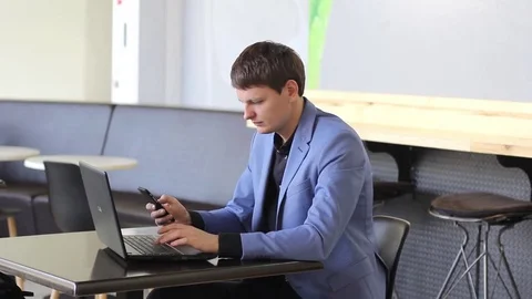 Young businessman working on computer and with the phone in a cafe Stock Footage 73964264