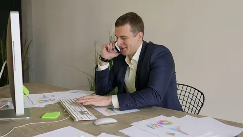 Young businessman working at the computer and talking on the phone Video stock 110944899