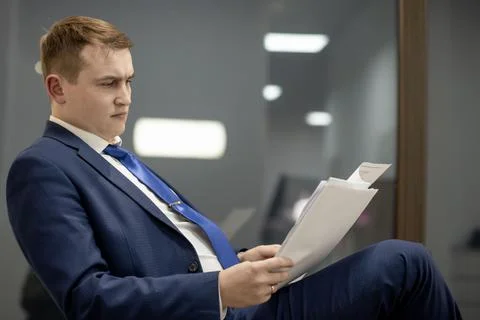 Young businessman working with documents looking through papers in folder, si Stock Photos