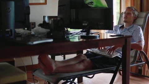 Young businessman working at home at computer in comfortable reclining Stock Footage 78176243