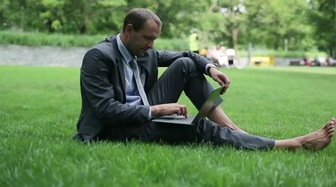 Young businessman working on laptop in the park HD Stock Footage