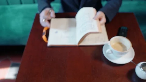 Young businessman is working with notebook, sitting at table in cafe interior. Stock Footage 89952875
