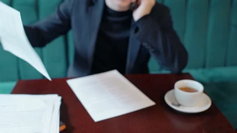 Young businessman is working on project, talking on phone in cafe interior. Stock Footage 90226047
