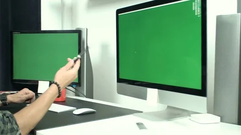 Young businessman working at table sitting in front of two monitors with green Stock Footage 79673846