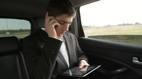Young businessman working with tablet on the back seat of car Stock Footage 12373887