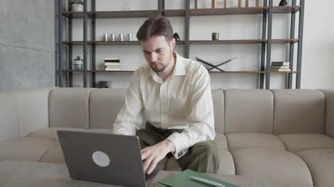 Young Businessman Working Using Laptop and Analyzing Documents on Sofa Stock Footage 299284412
