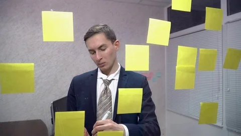 Young businessman writing on sticky notes in office Stock Footage 71928201