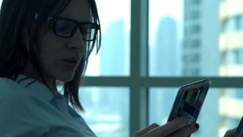 Young businesswoman comparing data on tablet and smartphone in office  Stock Footage 74996496