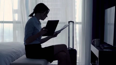 Young businesswoman comparing data on tablet and documents on bed at hotel Stock Footage 87699368