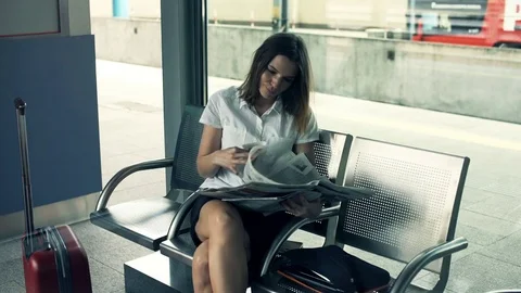 Young businesswoman reading newspaper sitting at the railway station Stock Footage