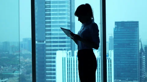 Young businesswoman using tablet computer standing by window in office Stock Footage 56400261