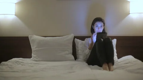 Young businesswoman using tablet computer lying on bed at night Stock Footage 60159383