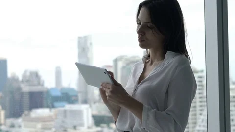 Young businesswoman using tablet computer standing by window at office Stock Footage 82498182