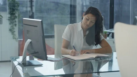 Young businesswoman writing notes while studying business graph on computer Stock Footage 108073751