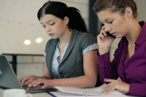 Young businesswomen working with cellphone and laptop in the office NTSC Stock Footage