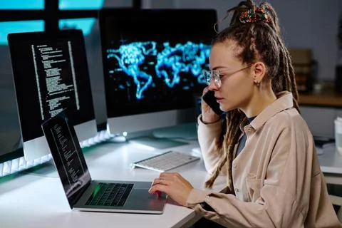 Young busy IT engineer taking call of client and checking information in laptop Stock Photos