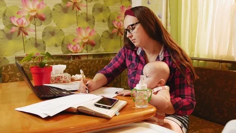 Young busy mother keep her baby and trying to work Stock Footage 122245662