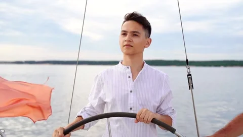 Young Captain at the helm of the sailboat. Video stock 163304174