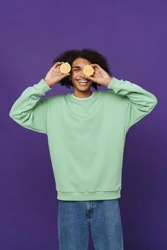 Young caribbean man smiling while making fun with lemon Stock Photos