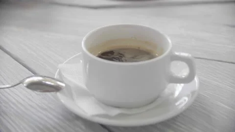 A young caring housewife is stirring sugar in a cup with hot aromatic coffee Stock Footage 155453553