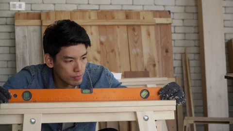 A young carpenter is checking the accuracy of the water level with his woodwork. 動画素材 125563638