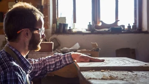 The young carpenter chooses a board that is covered with chips and dust. Hobby Stock Footage 84780653