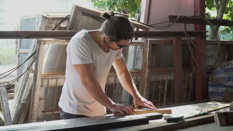 Young carpenter man using sandpaper on a piece of wood in workshop . Stock Footage 149985544