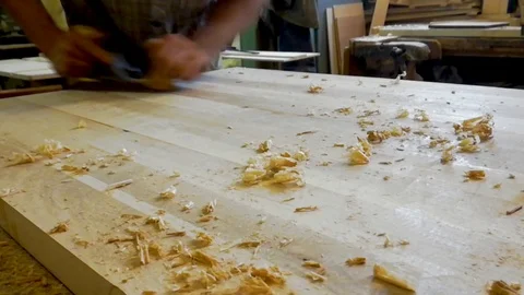 Young carpenter scribbles the table top with a plane Stock Footage 89573091