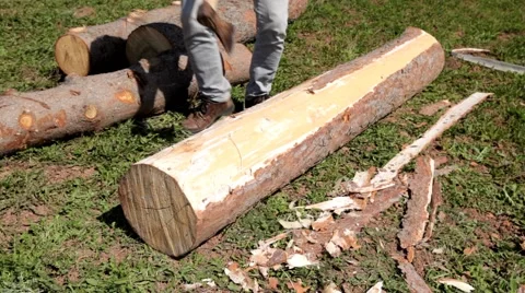 Young carpenter shells a log of pine with axe Stock Footage 51933399