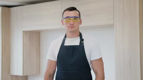 Young carpenter standing with arms crossed in bright room with new furniture Stock Footage 130452573