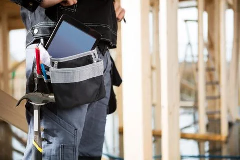 Young Carpenter With Tablet Computer And Tools In Bag At Site 写真素材
