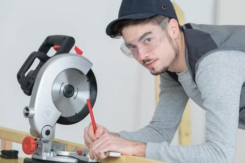 Young carpenter using circular saw for wood inside warehouse Foto stock