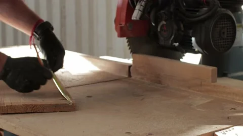 Young carpenter working on a circular saw  marking and cutting a wooden plank Video stock 173927875