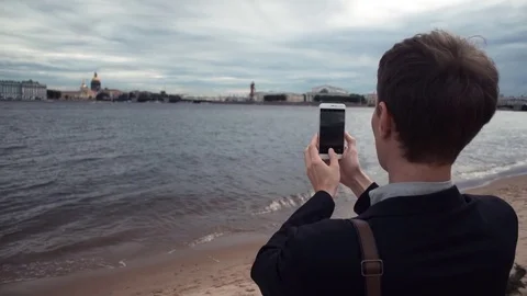 Young casual dressed man using laptop sitting on embankment. Working outdoors Stock Footage 80063300