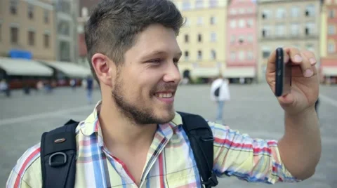 Young casual man with beard taking picture with camera phone outdoors. Видео 41480532