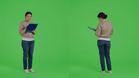 Young casual person looking at clipboard papers on full body greenscreen Stock Photos