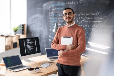 Young casual software developer with digital tablet standing by table 스톡 사진