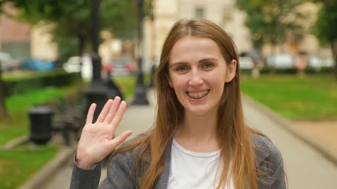 Young Caucasian blonde waves at the camera and smiles broadly. Video stock 139912022