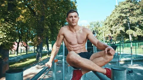 Young caucasian bodybuilder sitting on parallel bars resting after hard exercise Stock-Footage 148969935