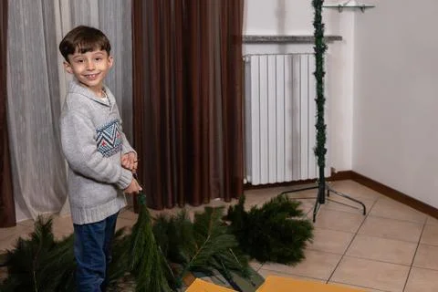Young caucasian boy assembling artificial christmas tree at home Stock Photos