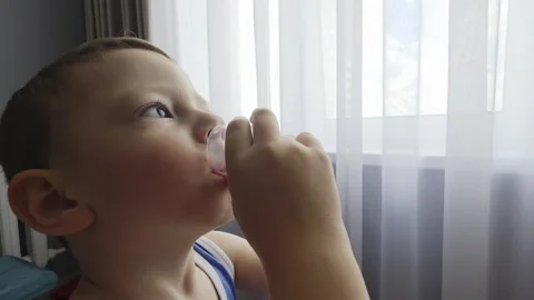 Young caucasian boy drinks cough medicine from a measuring cup, receiving Stock-Footage 341658022