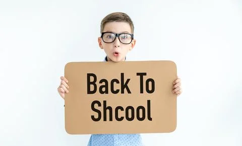 Young caucasian boy smiling while holding a card with text Back to Shcool o.. Stock Photos