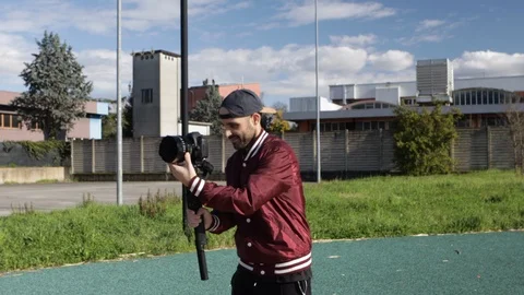 Young caucasian cameraman does a panoramic shot with his camera and cinema lens Stock Footage 125777425