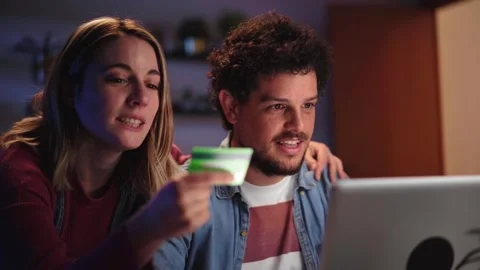 Young Caucasian cheerful couple using credit card for online shopping on laptop Stock Footage 258112075