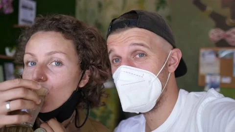 Young caucasian couple in face masks talking taking a selfie. Woman takes off Stock Footage 157441946