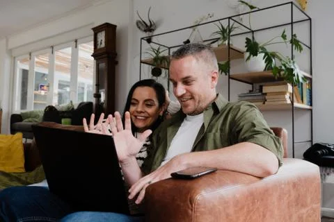 Young caucasian couple on video call with family on the computer at home Stock Photos