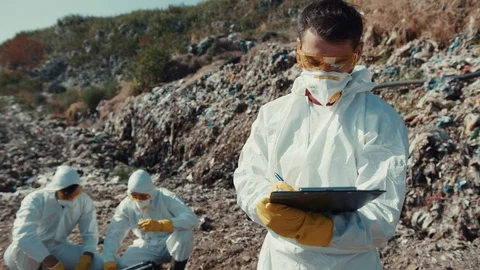 Young caucasian ecologist writing notes while analyzing disposal site on sunny Video stock 113929386