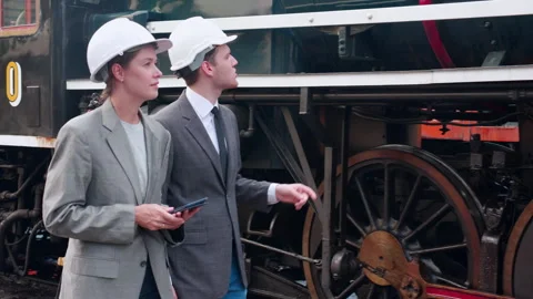 Young caucasian engineer man and woman in suit walking checking train with .. Stock Footage 257430969